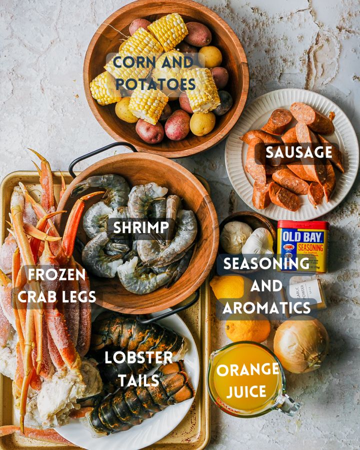 an assortment of seafood and other foods in bowls on a tray with the words corn and potatoes, shrimp, crab legs, lobster tails, lobster tails, orange juice