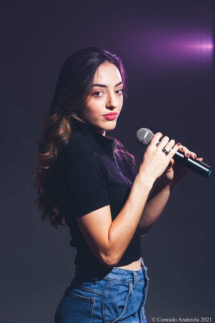 a woman holding a microphone in her right hand and looking at the camera with an intense look on her face