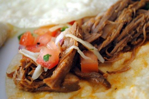 a close up of a taco with meat and vegetables on it next to tortilla bread