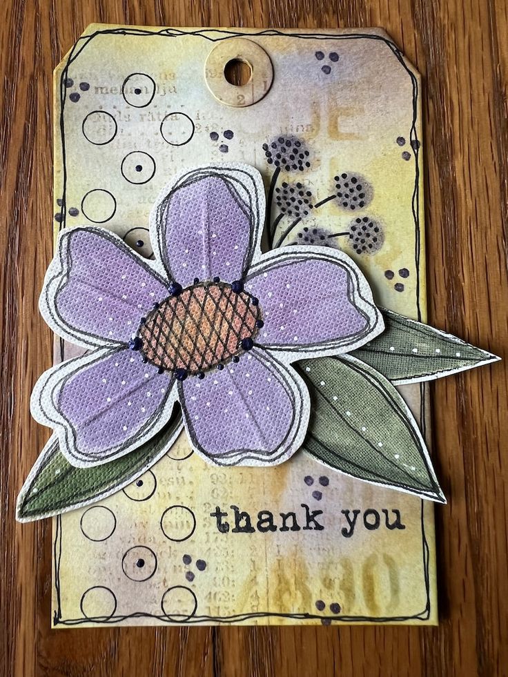 a close up of a thank you card on a wooden surface with flowers and leaves