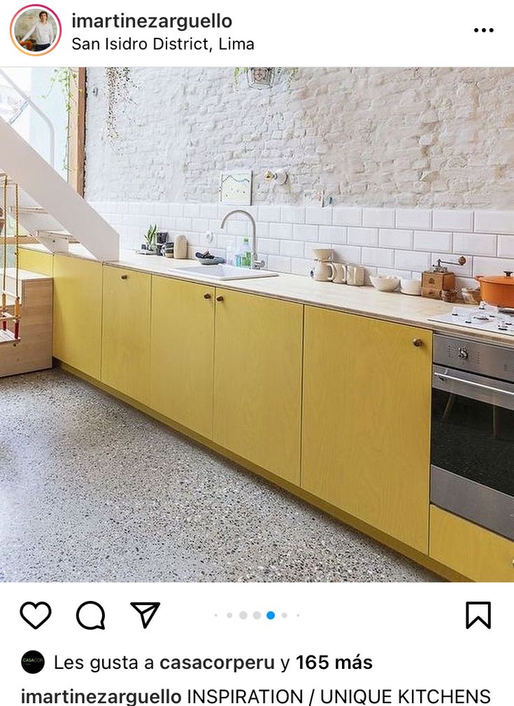 a kitchen with yellow cabinets and an open staircase leading up to the second floor area