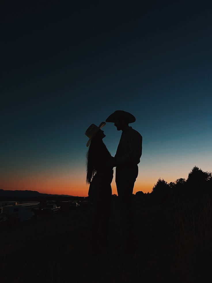 two people standing next to each other at sunset