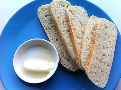 a blue plate topped with two pieces of bread and butter next to a bowl of yogurt