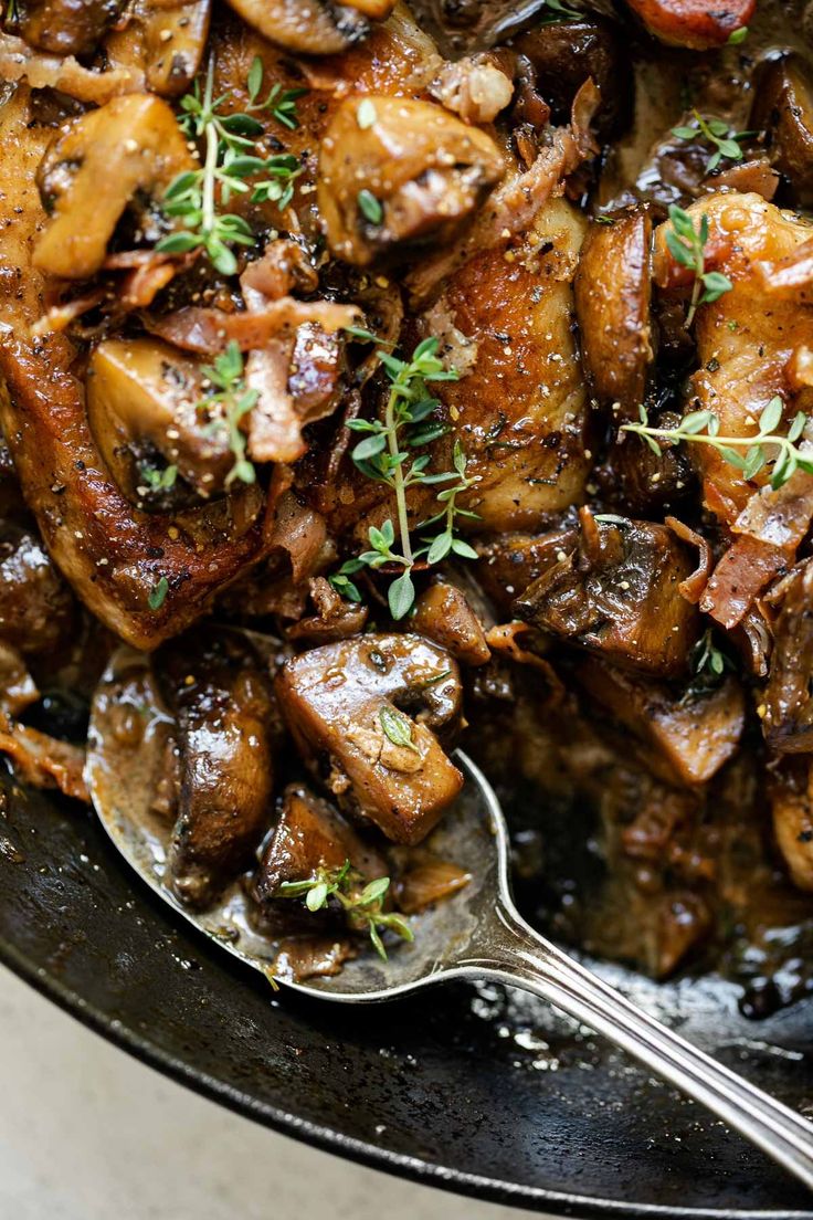 a skillet filled with cooked meat and garnished with herbs