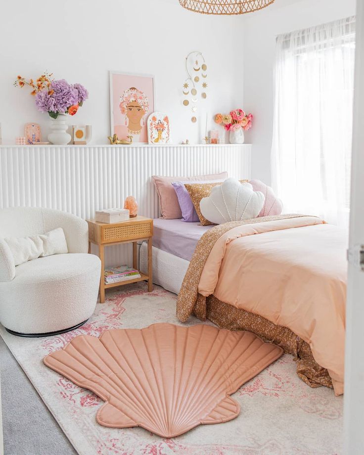 a white bedroom with pink and gold decor on the walls, bedding and rugs