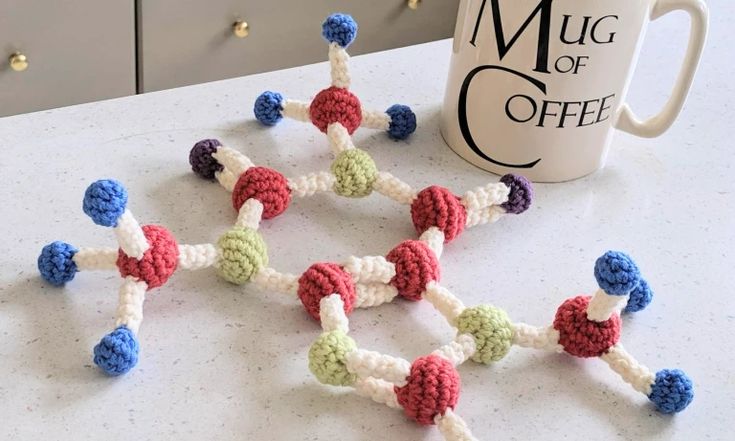 there are many small crocheted beads on the table next to a coffee mug