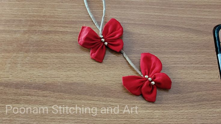 two red bows with pearls on them sitting next to a cell phone