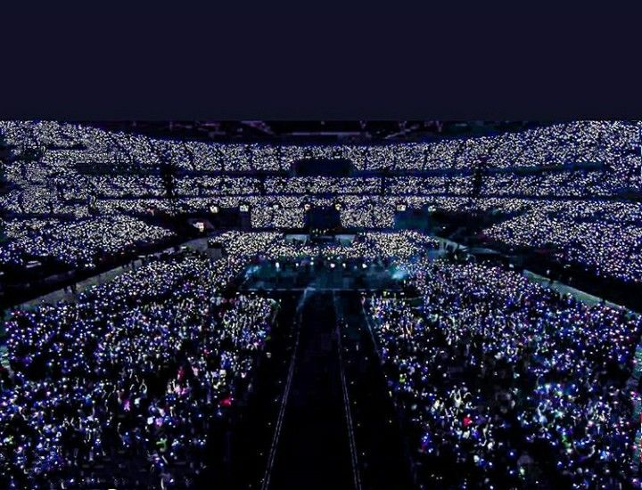 an aerial view of a large crowd at a concert with bright lights on the ground