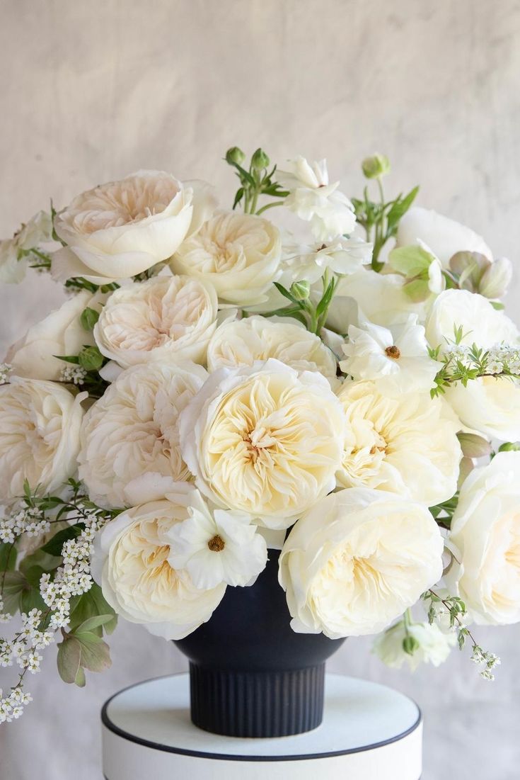 a black vase with white flowers in it