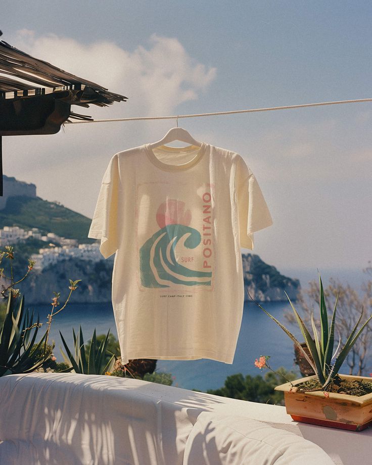 Seize the surf in our Positano 1980 Tee. For the girl who makes waves both on the beach and off, this is your summer statement tee. Unisex soft cotton crew neck t-shirt featuring a Positano Italy Surf Camp graphic printed on the front. Fabrics: 100% cotton, 6 oz Made in: LA Statement Tees Aesthetic, Surf Brands Clothing, Beach Graphic Tee, Surf Merch, Summer Graphic Tees, Beach Shirt Design, Surf Baby, Surf Fashion, Beach Tshirt