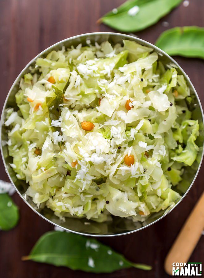 a metal bowl filled with coleslaw on top of a wooden table