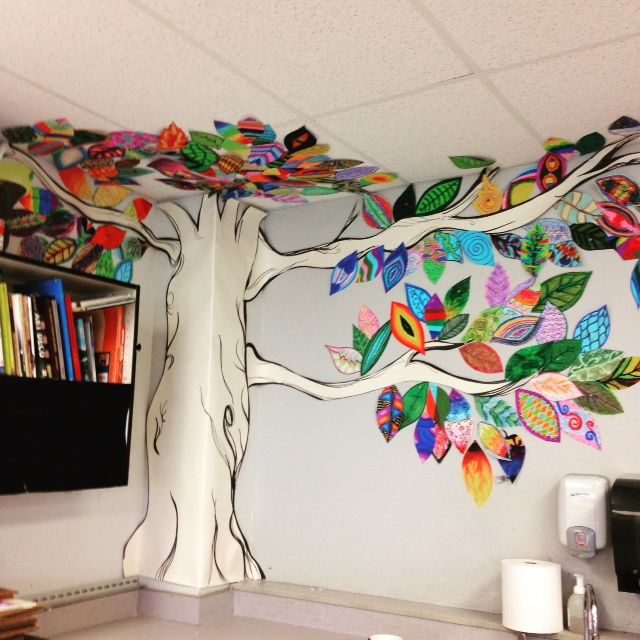 a tree painted on the side of a wall with bookshelves in front of it