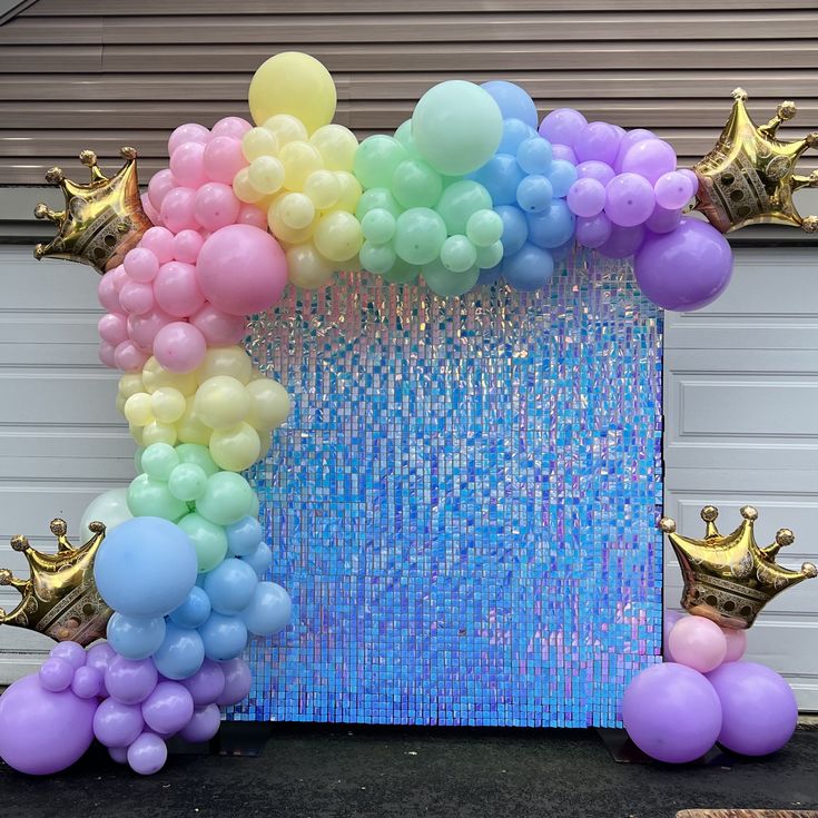 there is a large balloon arch with balloons on it and some gold crowns around it