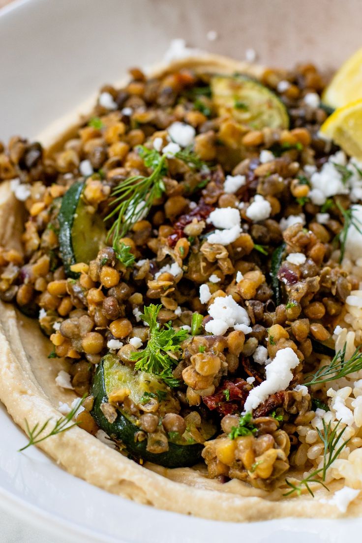 a white bowl filled with food on top of a table next to a lemon wedge