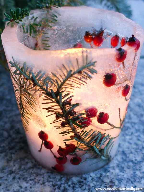 a glass filled with ice and berries on top of a table next to a plant