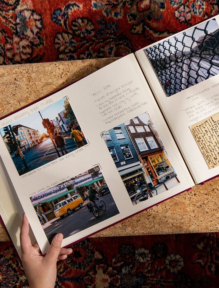 an open book with pictures on it sitting on top of a table next to a person's hand