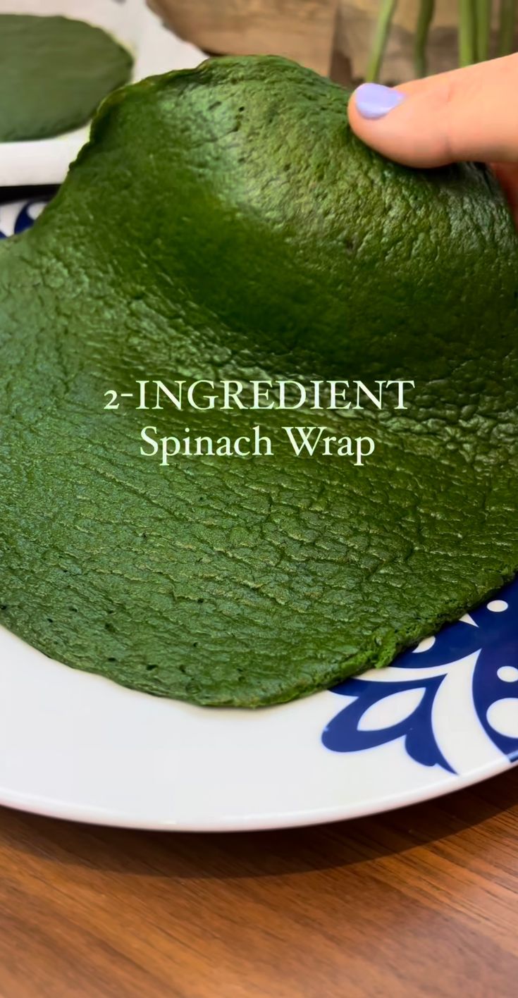 a person is holding up a green hat on a plate with the words 2 ingredient spinach wrap