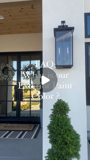 the front entrance to a house with an open door and two plants on each side