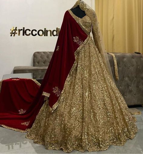 a woman in a red and gold lehenga is standing next to a couch