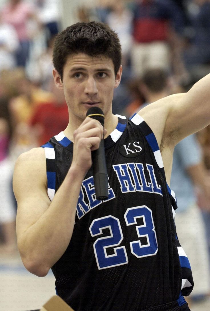 a young man holding a microphone in his right hand and wearing a jersey with the number 22 on it