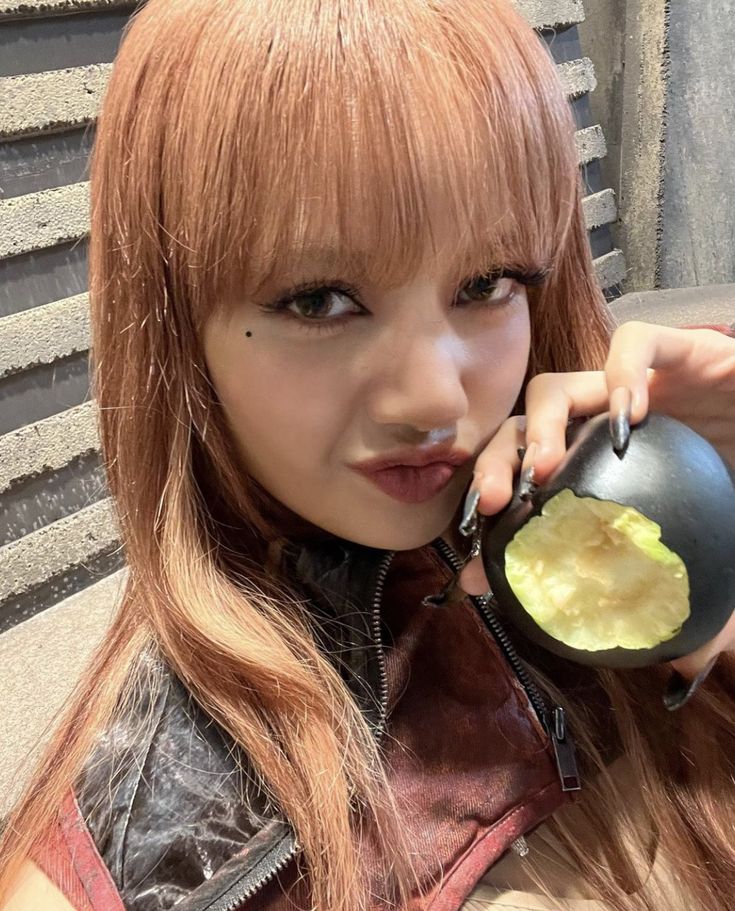 a woman with long red hair is holding an apple in her hand and looking at the camera