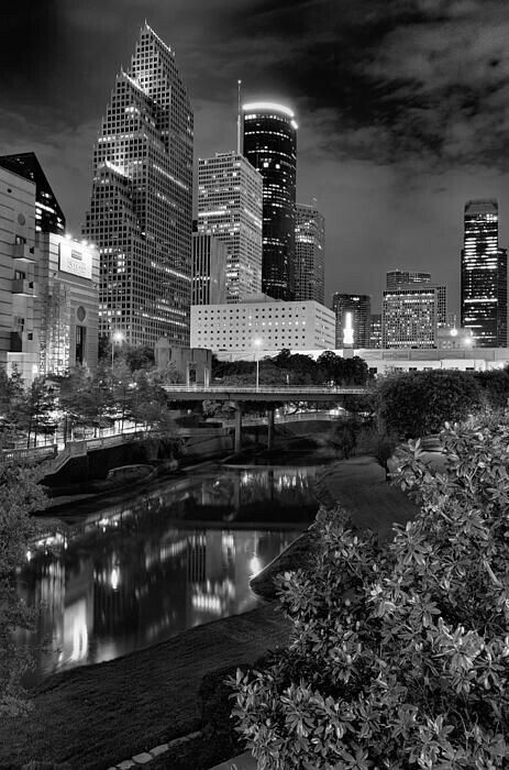 a black and white photo of the city at night with lights reflecting in the water