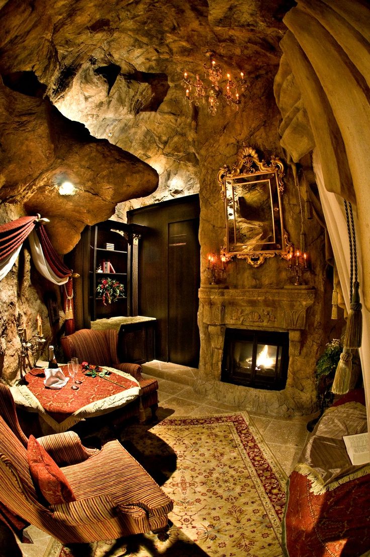 a living room filled with furniture and a fire place next to a stone wall covered in rocks