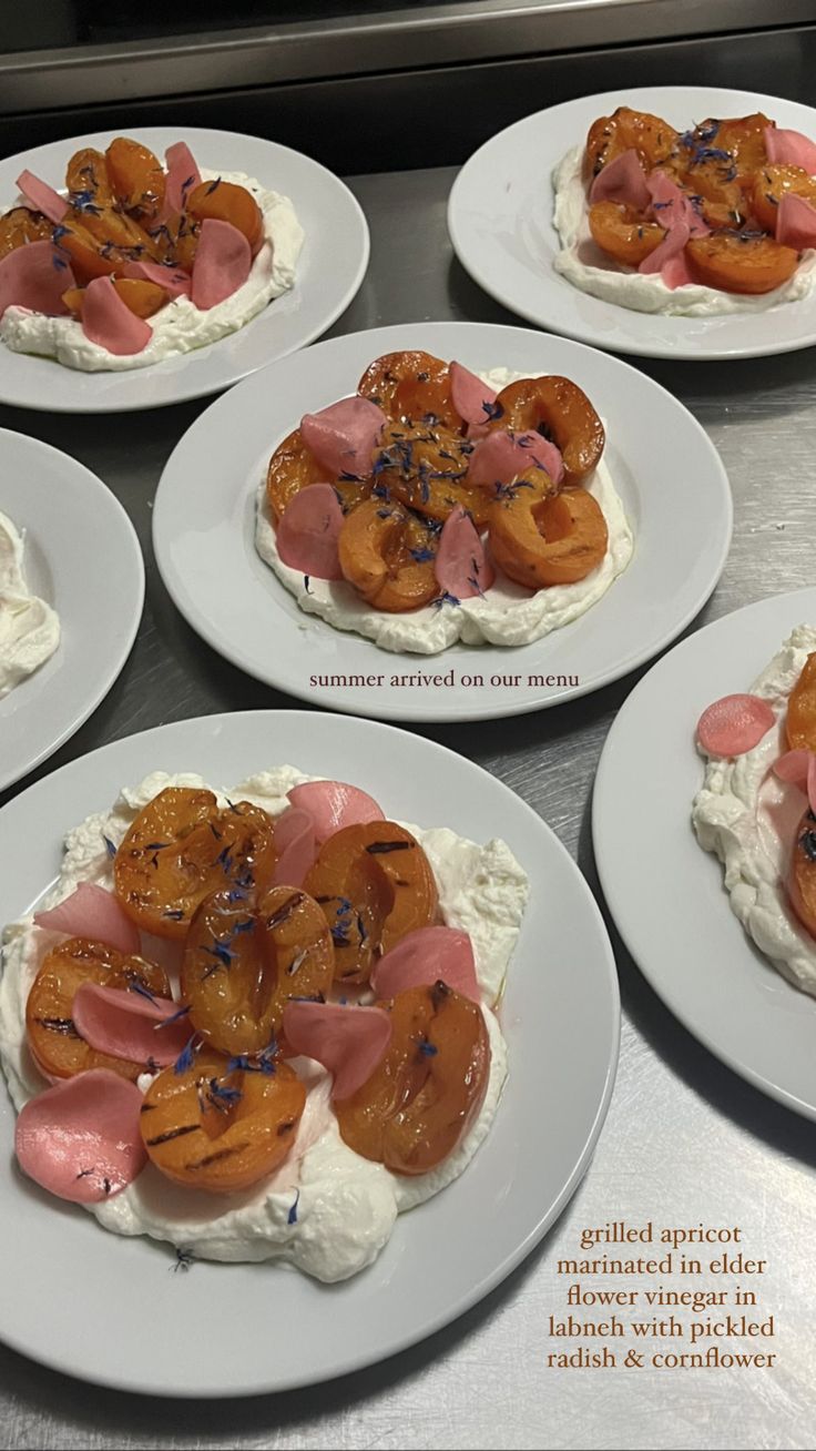 four white plates with food on them sitting on a counter top next to each other