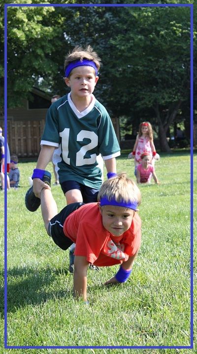 two young boys are playing football in the grass with their hands on each other's hips