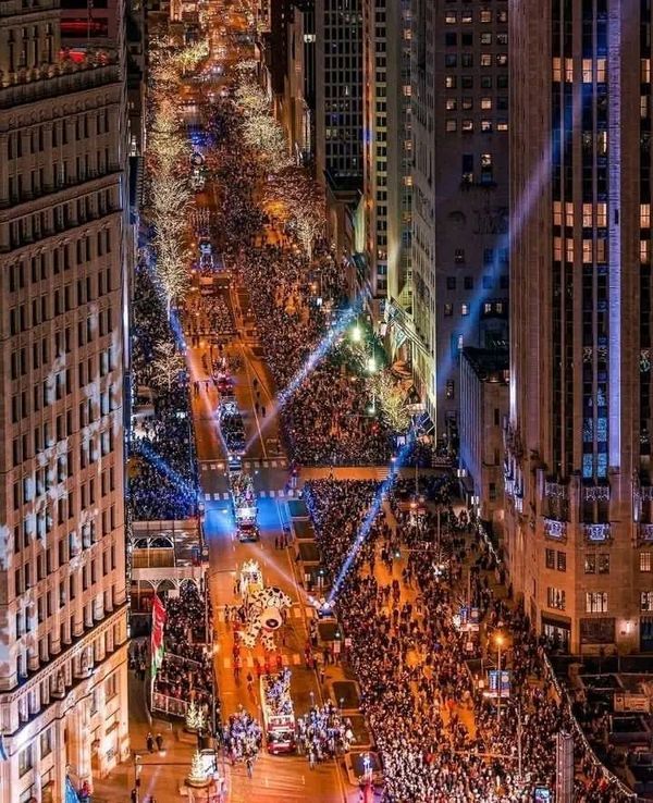 an aerial view of a city street at night with lots of people on the sidewalks