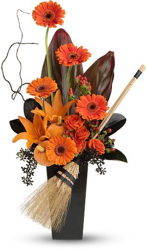 an arrangement of flowers in a black vase with brooms and leaves on the side