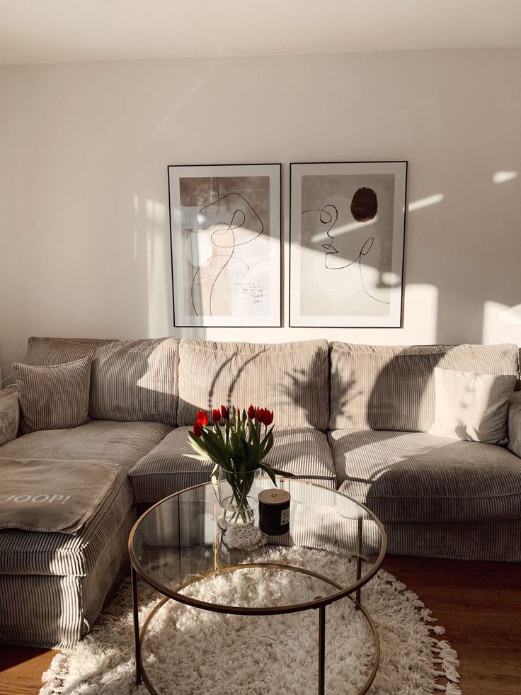 a living room with a couch, coffee table and two pictures on the wall above it