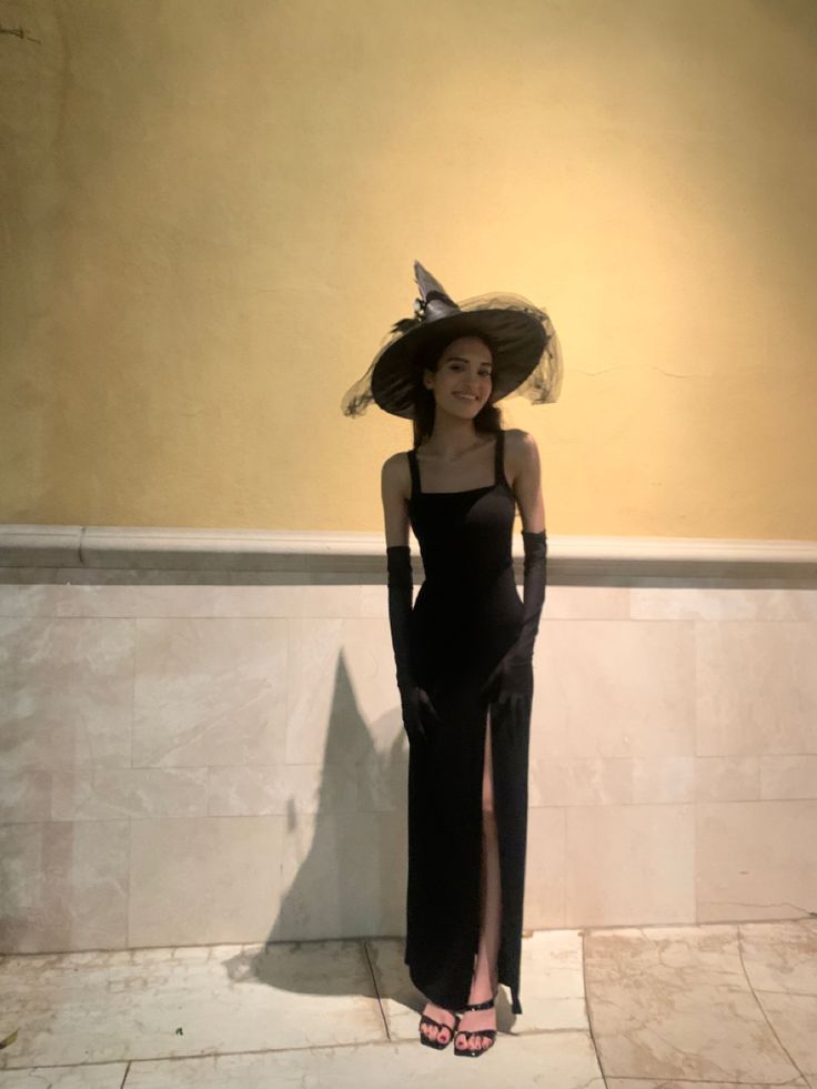 a woman in a long black dress and hat