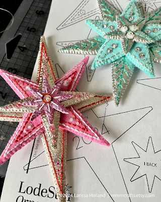 two star shaped ornaments sitting on top of a piece of paper