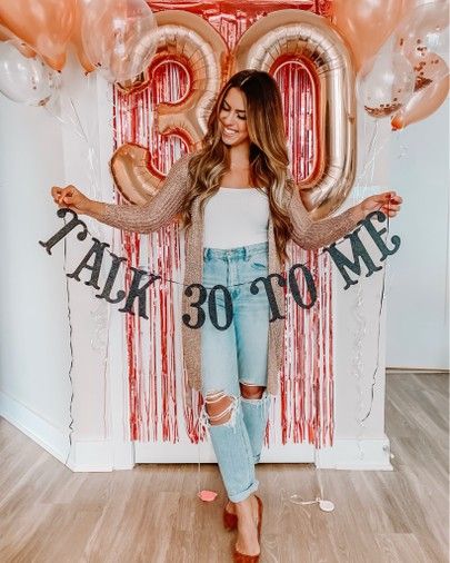 a woman standing in front of balloons with the number twenty on it