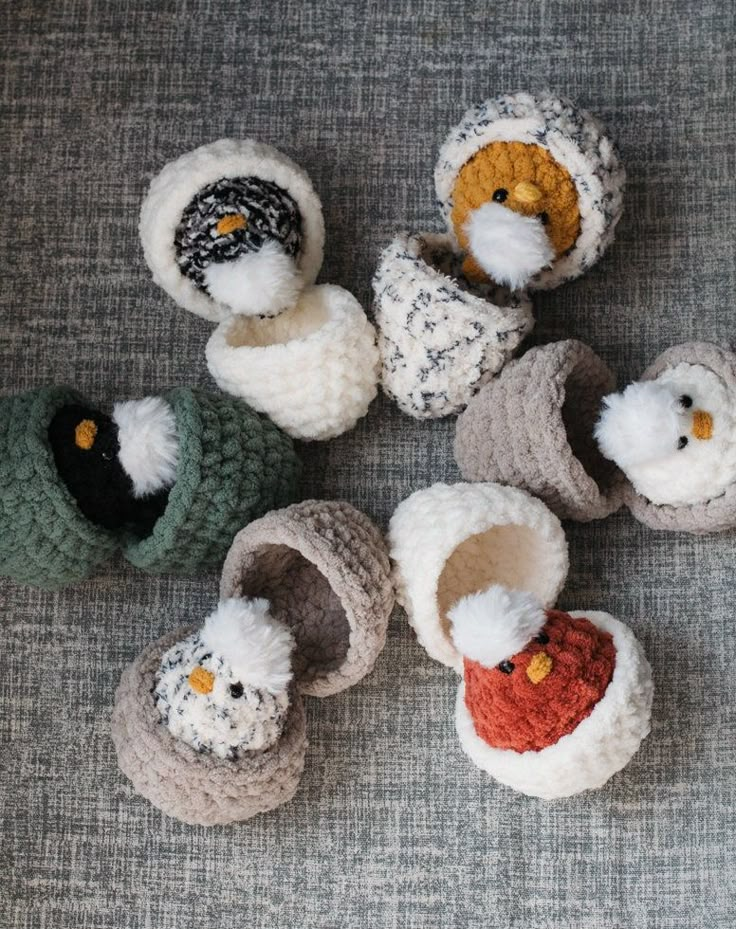 several crocheted baby shoes with stuffed animals in them sitting on a gray surface