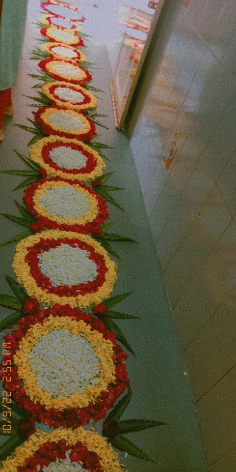 a long row of flowers on the ground in front of an aisle that is decorated with red, yellow and white flowers