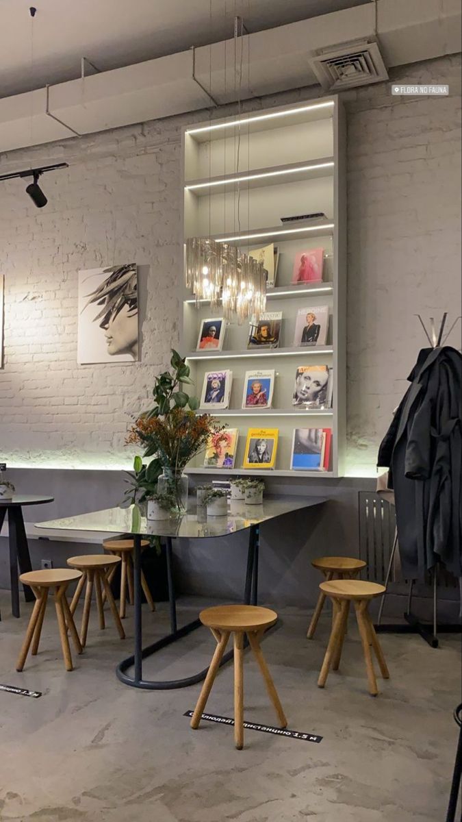 an empty room with several stools and tables in front of a book shelf filled with books