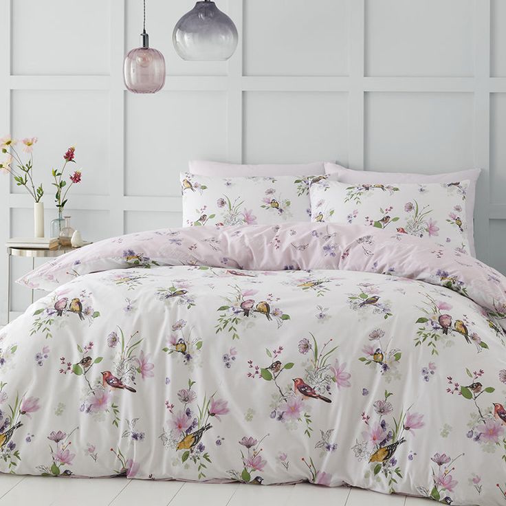 the comforter is made up with flowers and birds on it, along with two lamps