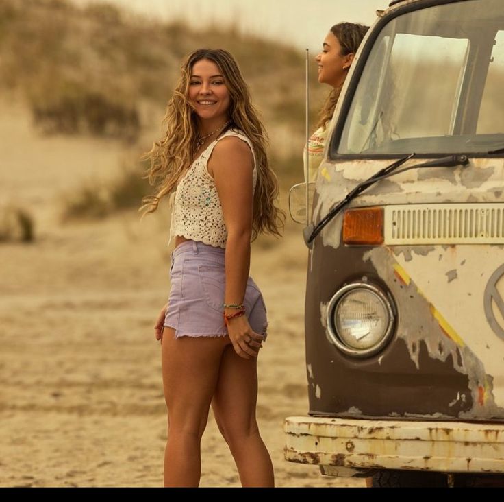 two women standing in front of an old van