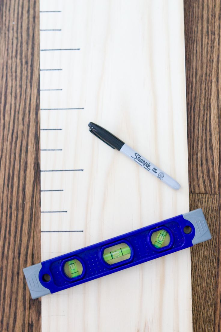 a blue ruler sitting on top of a wooden table next to a pen and marker