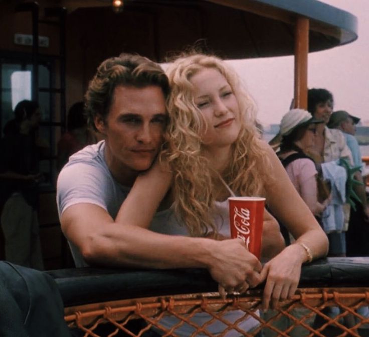 a man and woman sitting next to each other with coca - cola cups in their hands