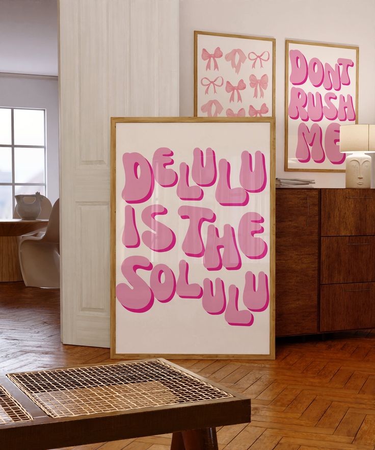 two pink posters on the wall in a room with wooden flooring and white walls