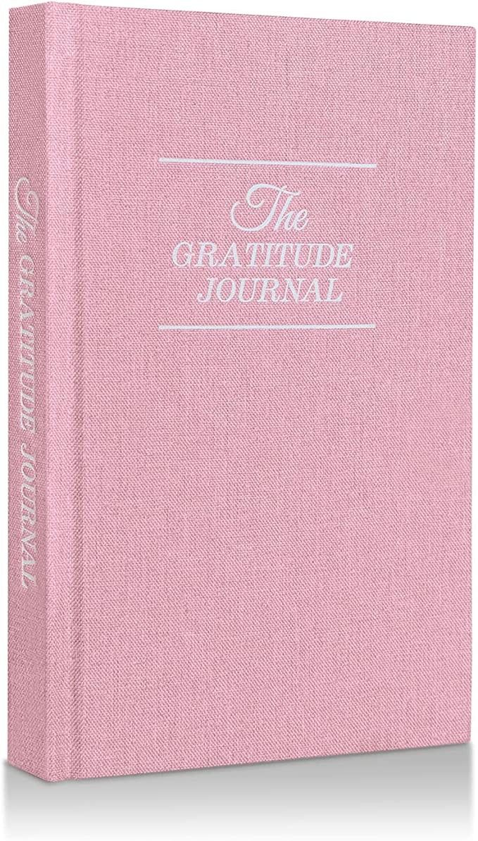 a pink book with white lettering on the front and back cover, which reads the gratitude journal