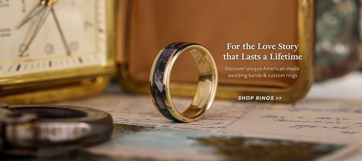 a wedding ring sitting on top of a table next to a pocket watch