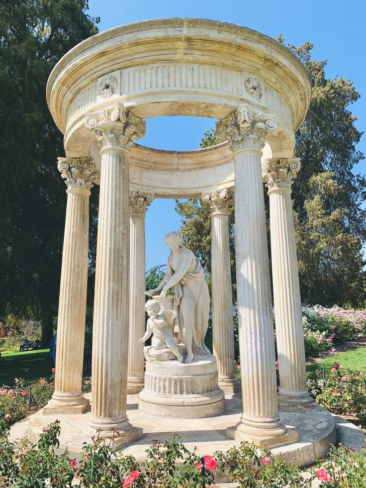 a statue in the middle of a garden surrounded by flowers