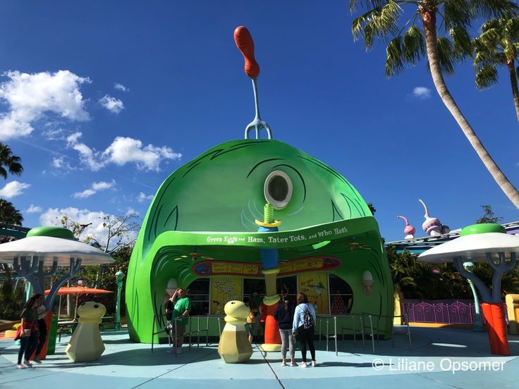 people standing in front of a green building with an eye on it's roof