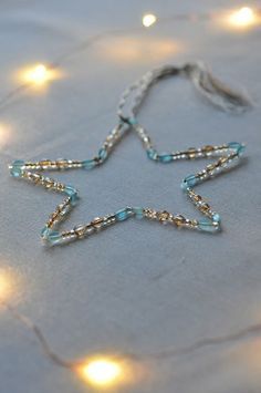 a star made out of glass beads on a table with lights in the back ground