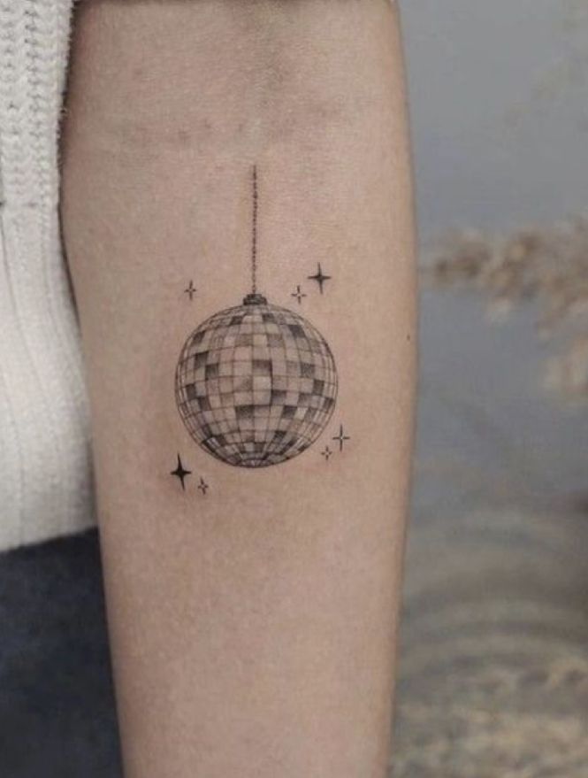 a person with a small tattoo on their leg that has a disco ball hanging from it