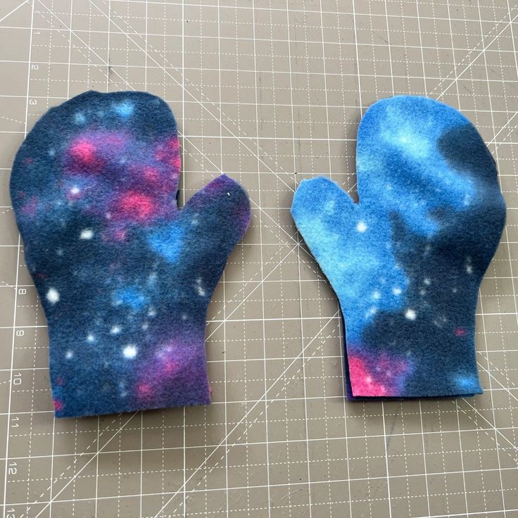 two oven mitts sitting on top of a cutting board with space printed on them